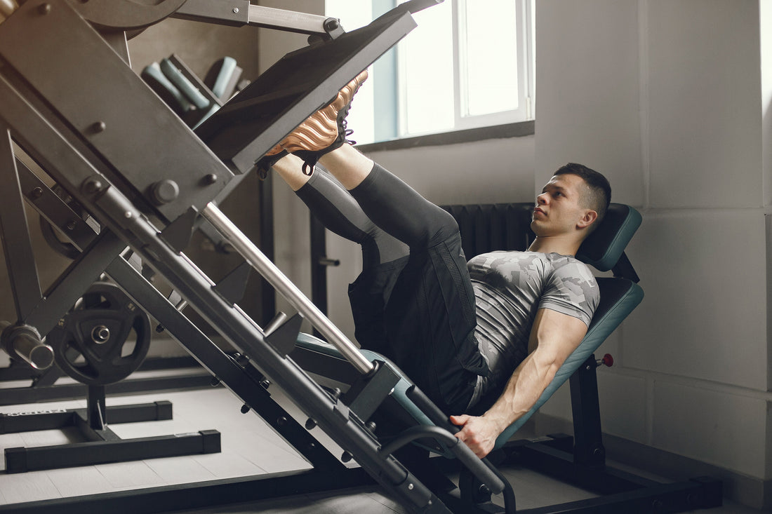 A man sits on a front squat machine, actively participating in a workout at the gym.