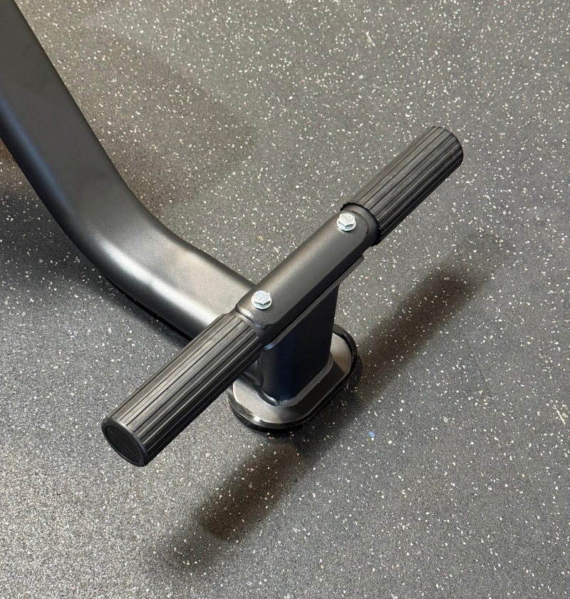 Up-close photo of the footrest on a black tricep seat on speckled flooring