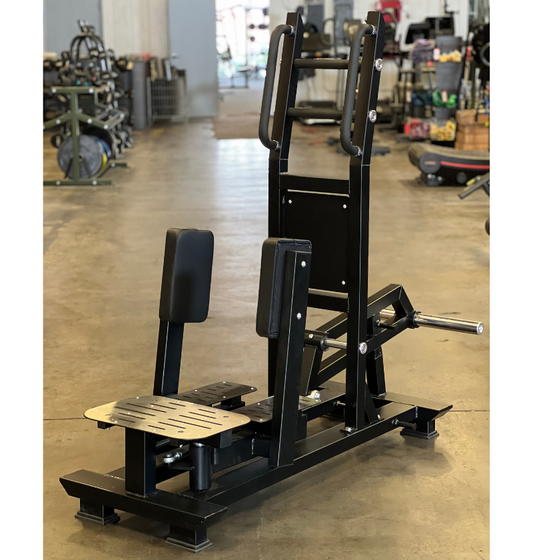 The J6503 Standing Abductor squat machine is prominently placed in the center of a large warehouse environment.
