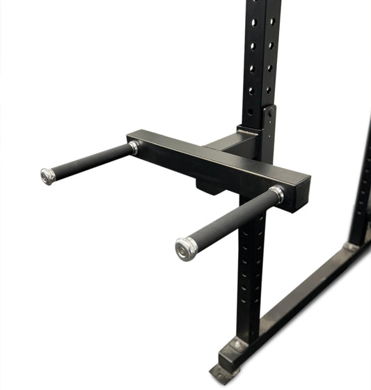 A black dip attachment for a power rack with two parallel bars and a central connecting bar, designed for upper body strength exercises.