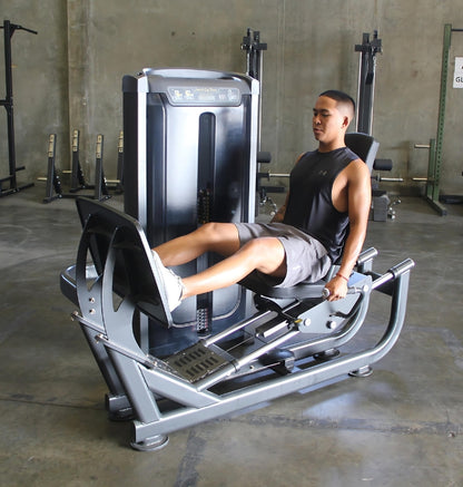 A man using a seated leg press machine in a gym, with a note stating pre-order availability in 8-10 weeks.