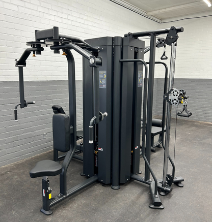 A multi functional trainer machine in a gym room with a white brick wall, providing versatile options for strength workouts.