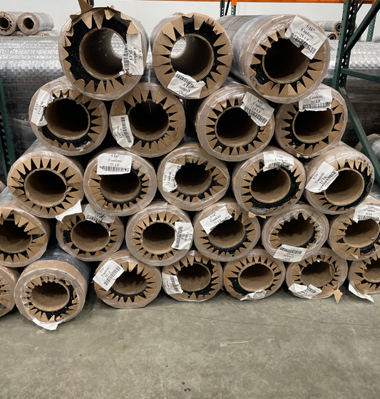 A warehouse filled with a stack of cardboard rolls labeled 'Rolled Flooring 5/16" Confetti'.
