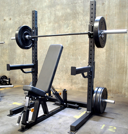 A black 6ft Basic Squat Rack with a pair of spotter arms, j-hooks, and weight peg holders, accompanied by a power bar and an adjustable bench.