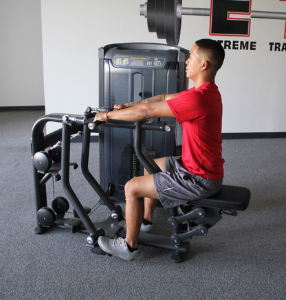 In a gym, a man engages in Compound Rows using a machine, emphasizing his workout routine and fitness goals.