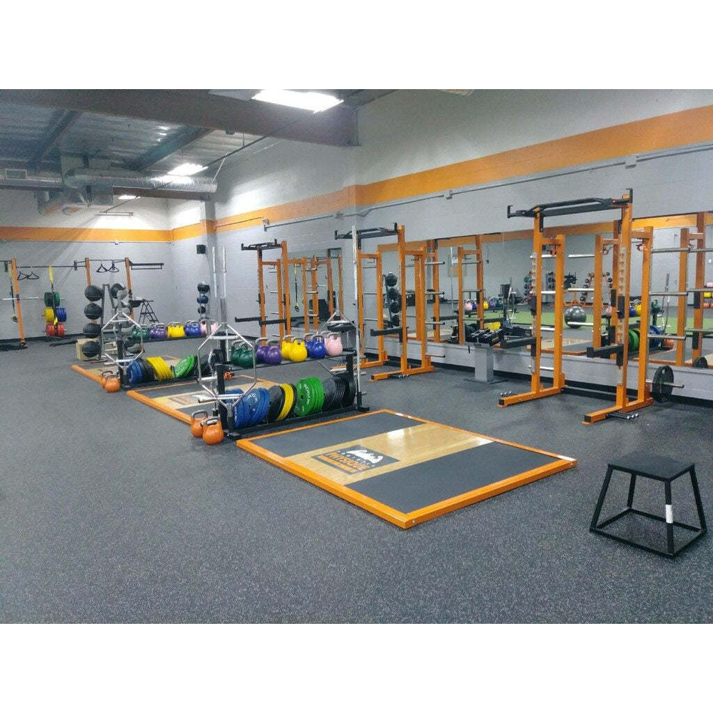 A gym interior featuring various exercise equipment, including Olympic lifting platforms. 