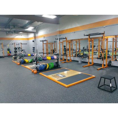 A gym interior featuring various exercise equipment, including Olympic lifting platforms. 
