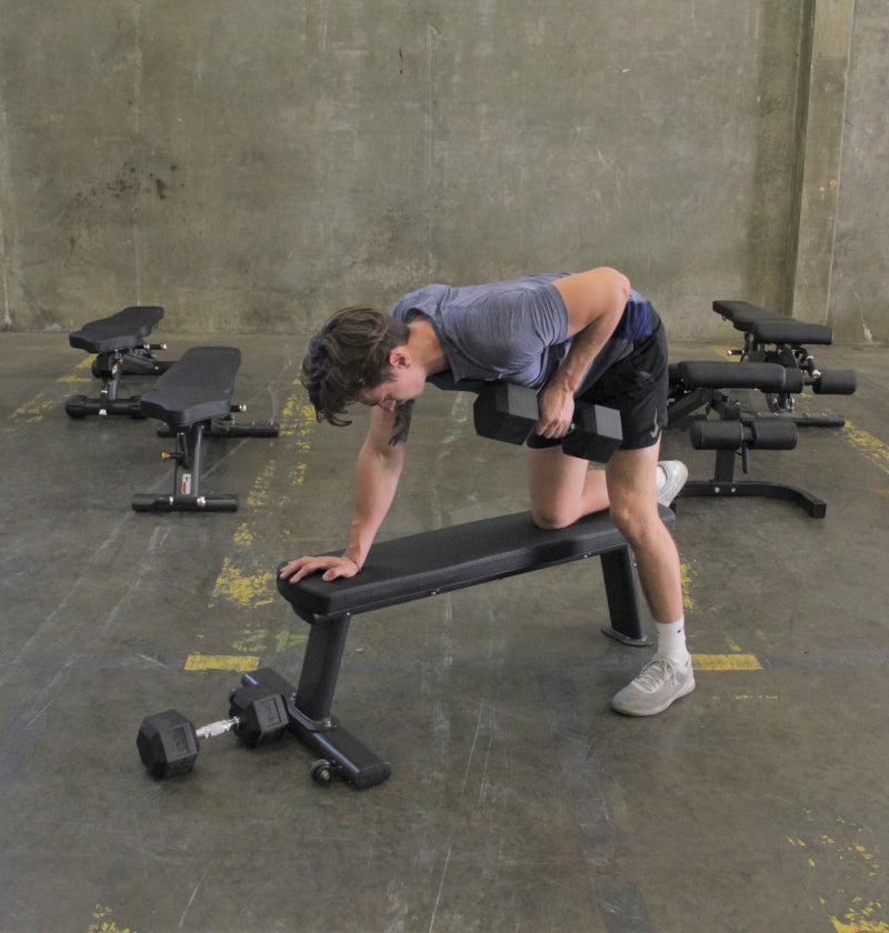 Person working out with dumbbell, on black gym flat bench. 