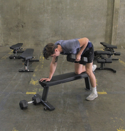 Person working out with dumbbell, on black gym flat bench. 
