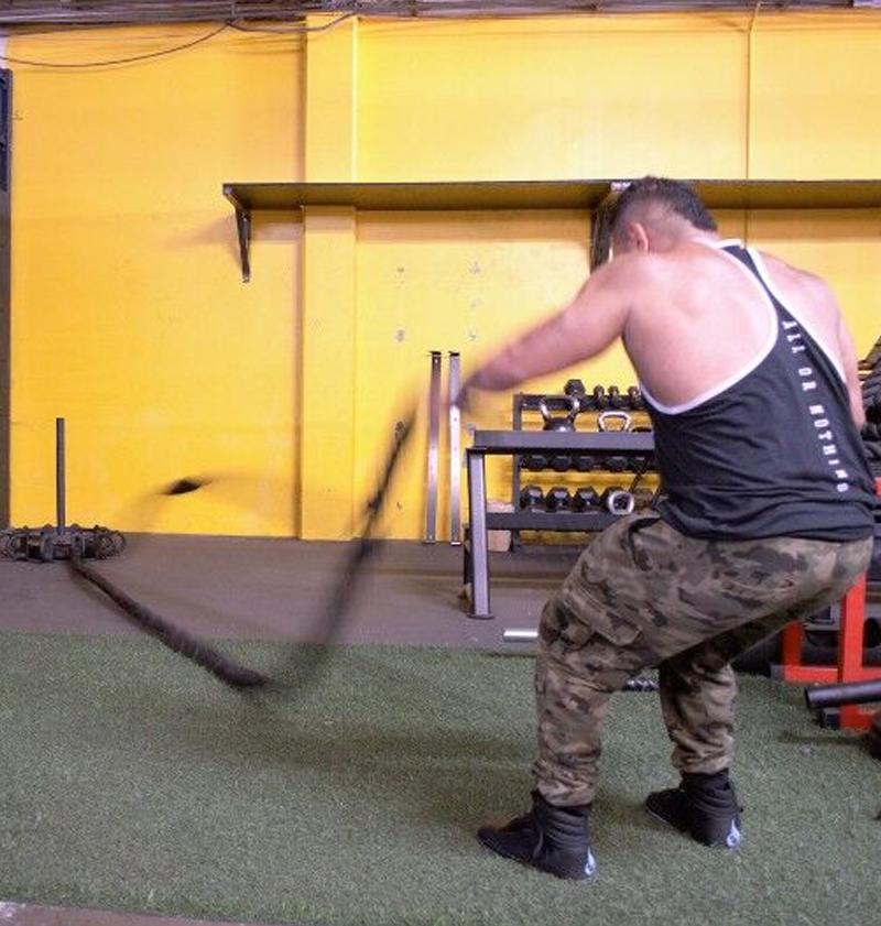 Man using battle rope in a gym setting 